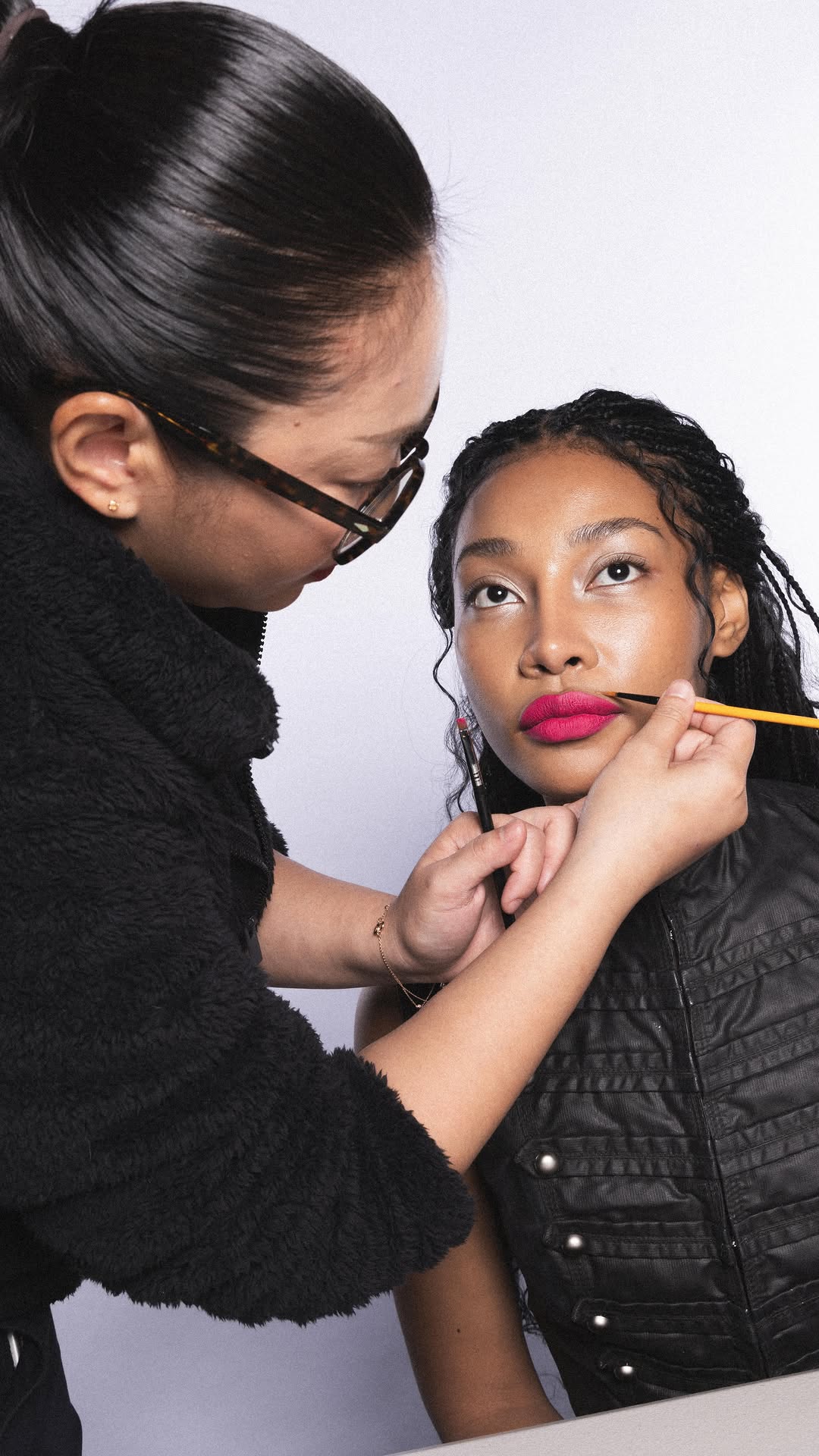 MUA applying lip colour on model, behind the scenes